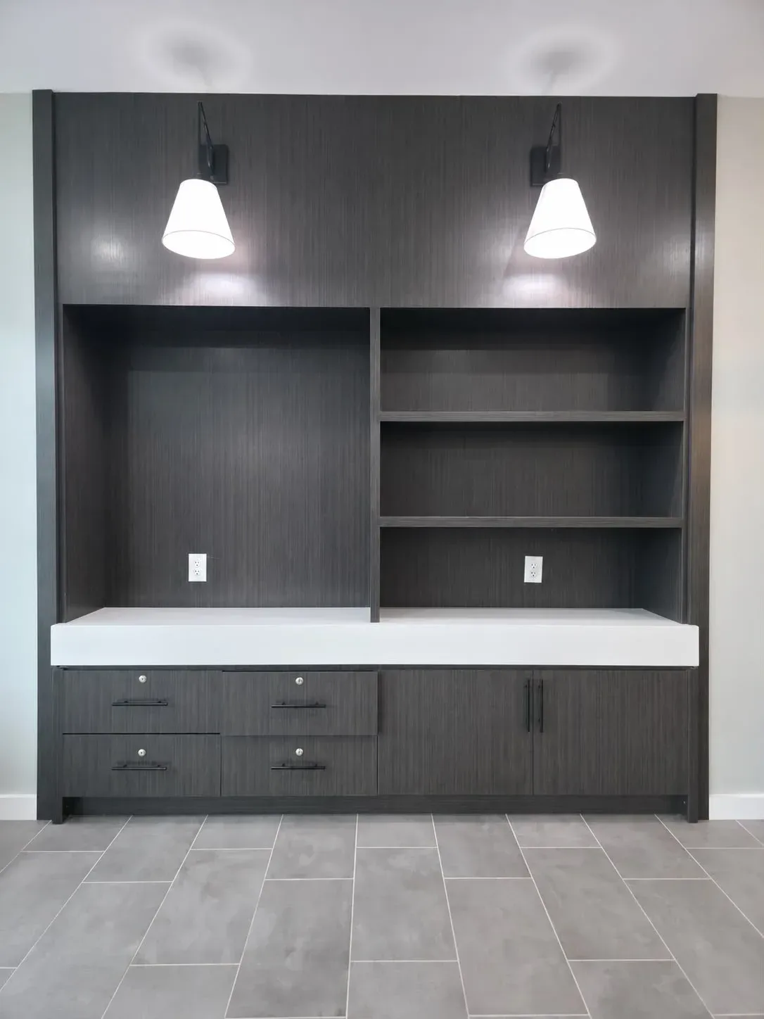 Dark laminate market cabinet with open shelving, drawer bank, door storage, and white quartz countertop